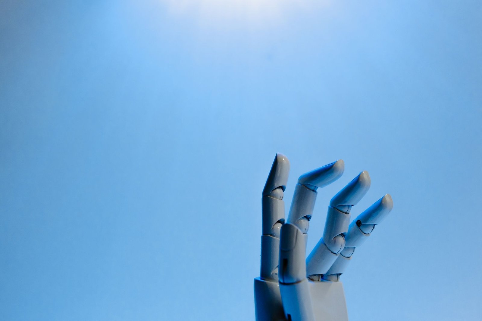 Mano robótica con dedos articulados sobre fondo azul, imagen para explicar qué es un agente de IA