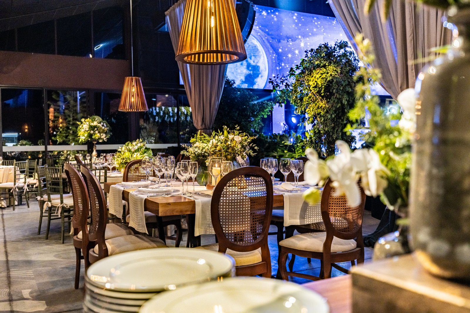 Salón de restaurante vacío en tonos azulados, con sillas elegantes y flores, listo para recibir reservas online para restaurante